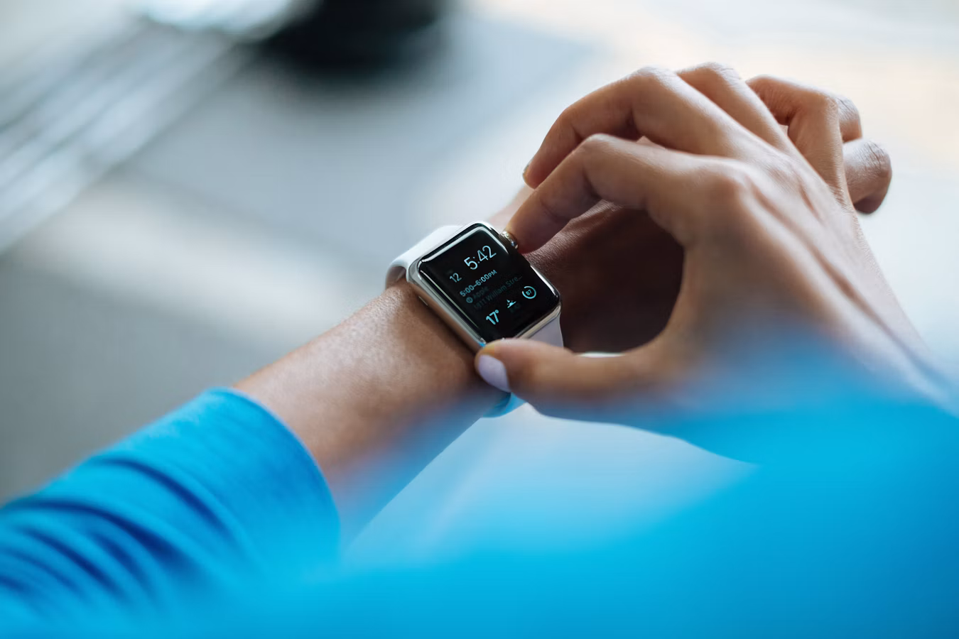 A modern smart watch next to a laptop displaying calendar